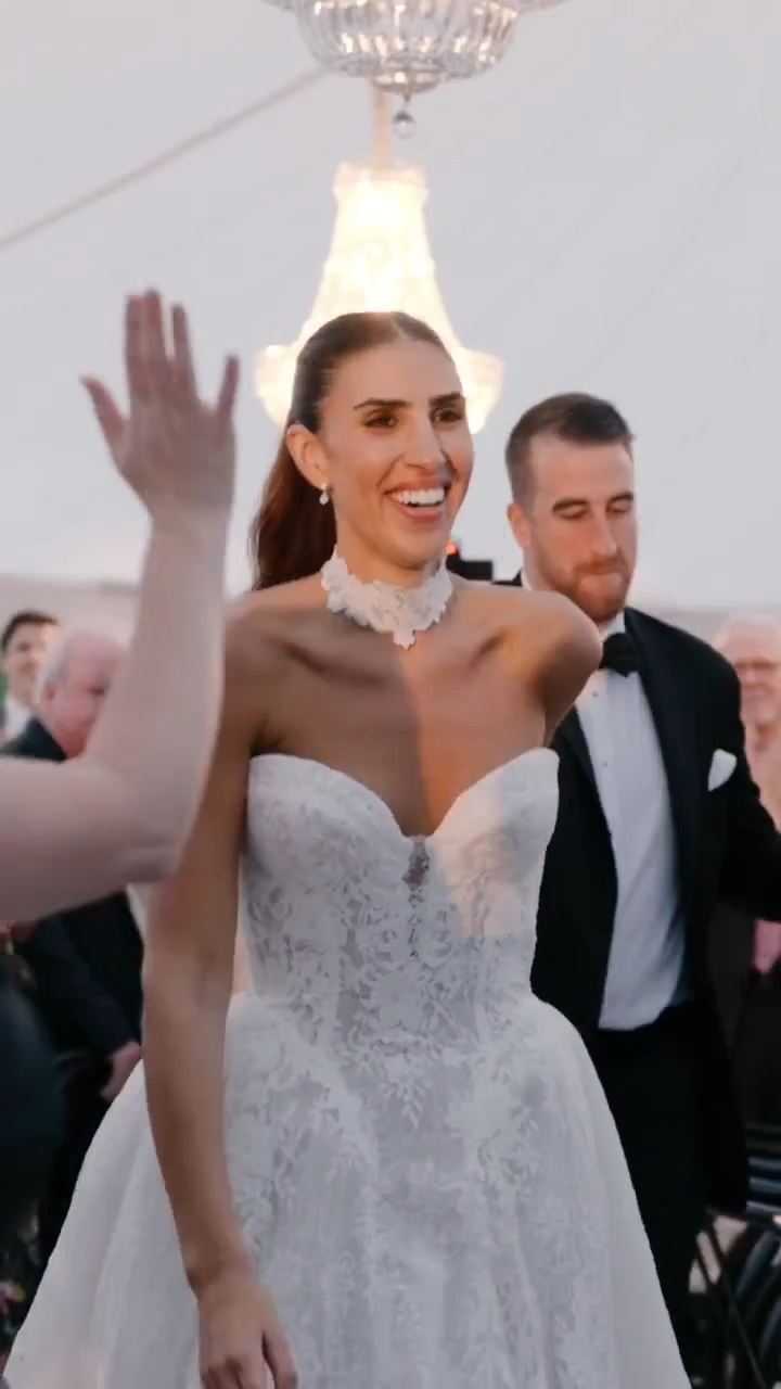 A smiling bride celebrating with the groom and wedding guests behind her